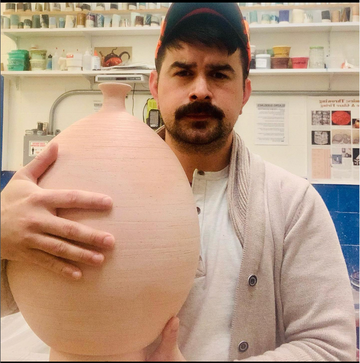 Portrait of Justin Hershey, ceramicist and restaurateur at Chicano Boy holding vase