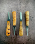 A set of four oyster knives with wooden handles and steel blades, displayed side by side on a textured metal surface.