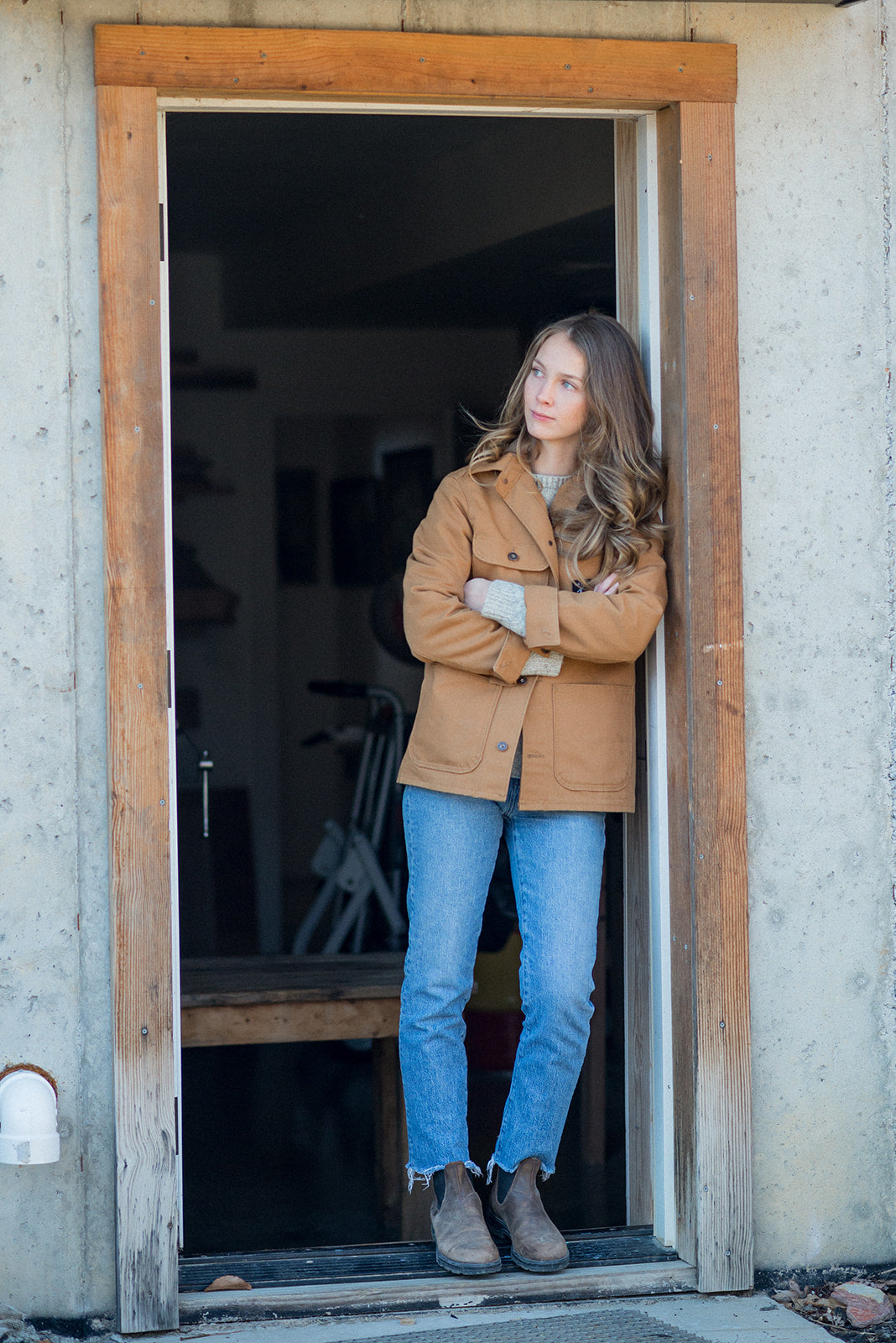 Portrait of Jacqui Stewart, artist, learning against doorway looking off into distance