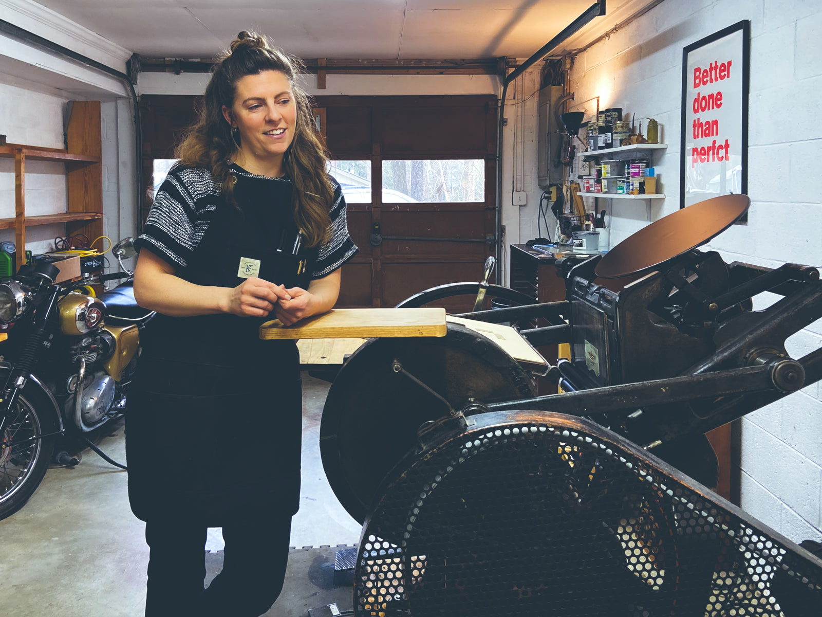 Portrait of Colby Beck, printmaker at Post Rider Press leaning on letterpress in garage studio