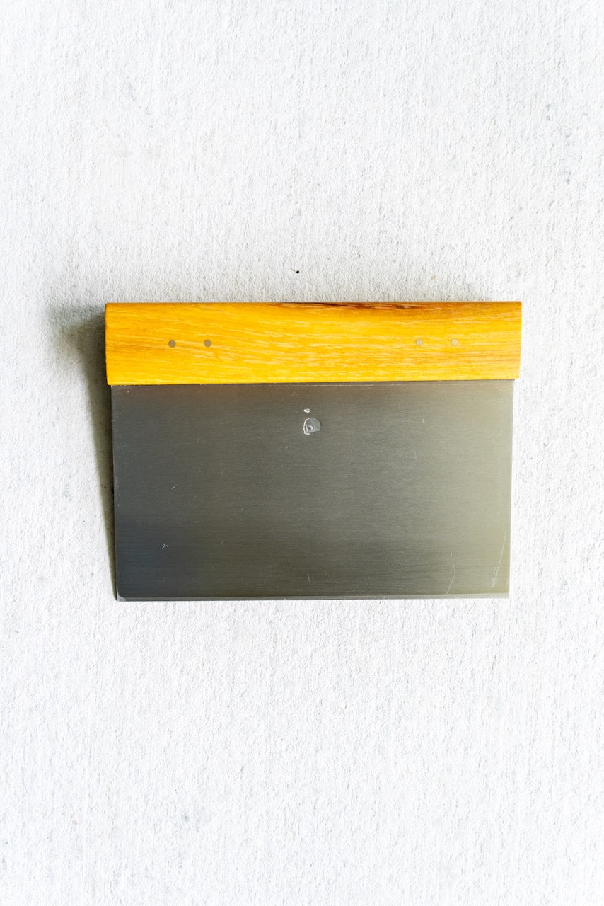 Metal bench scraper  with wooden handle on a white background