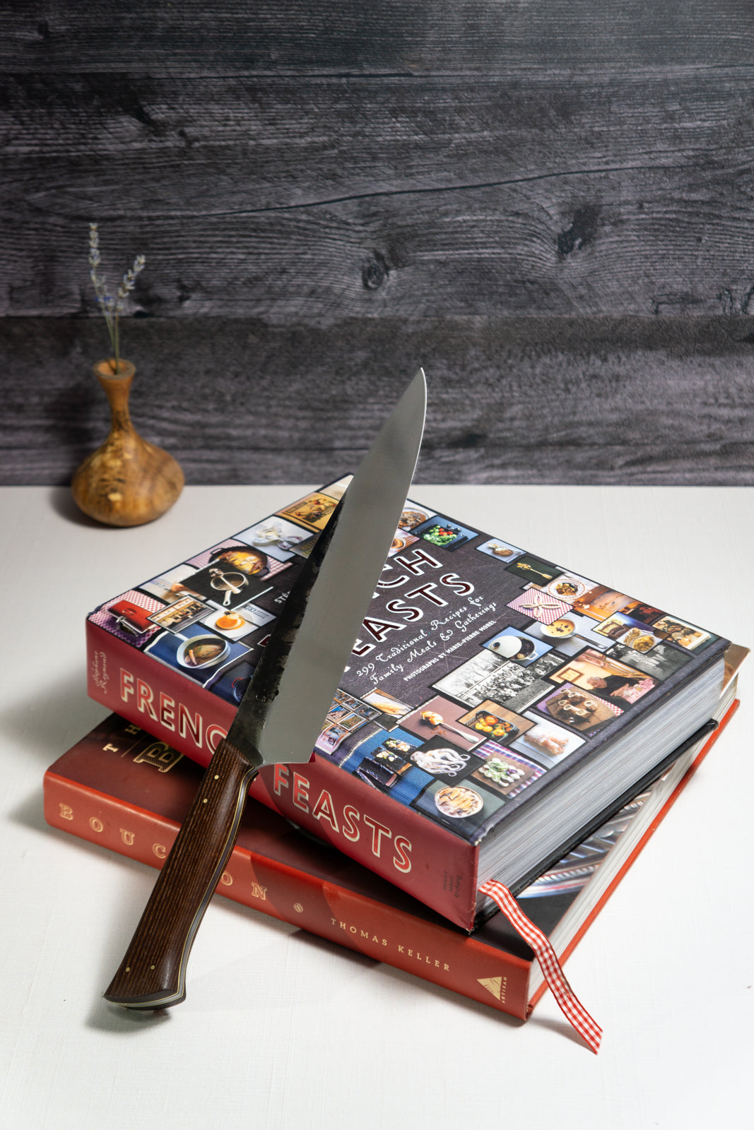 A 9-inch chef knife with a wooden handle, placed on top of two cookbooks, with a dark wooden background.